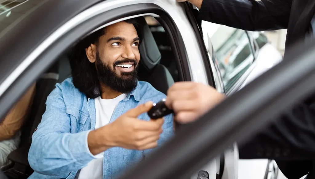 Smiling Man Receiving Car Keys From Salesperson at Vehicle Dealership