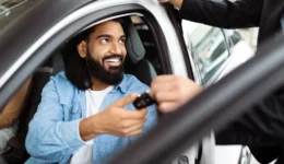 Smiling Man Receiving Car Keys From Salesperson at Vehicle Dealership