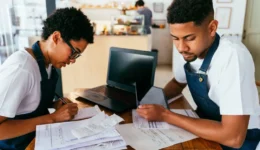 Barista and waiter working in a bar cafeteria shop calculating costs and taxes