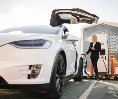 Woman using smartphone and charging car outdoors