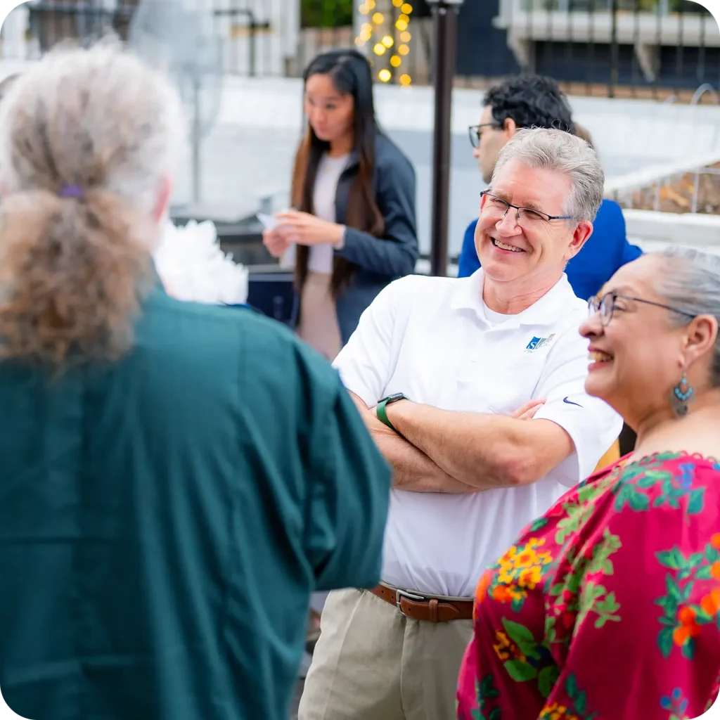 SDA CPA team member speaking with guests at an outdoor networking event.