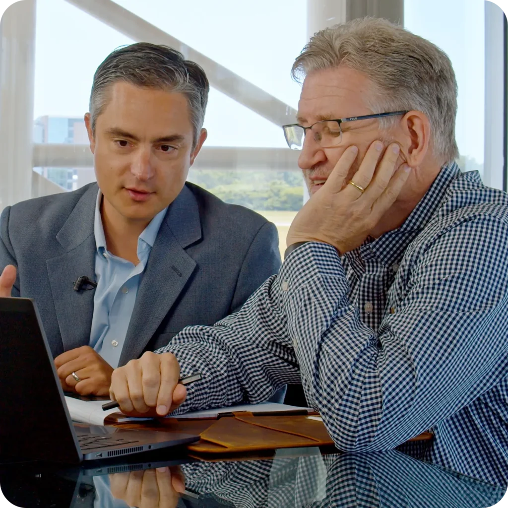 Two men reviewing financial information together on a laptop during a meeting.